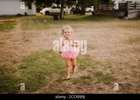 Glückliches kleines Mädchen in einem Tutu läuft auf einer Wiese Stockfoto
