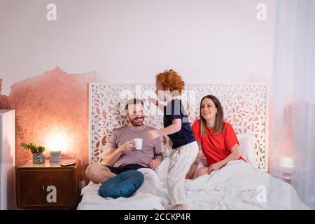 Eltern schauen auf verspielten Sohn beim Entspannen auf dem Bett Stockfoto