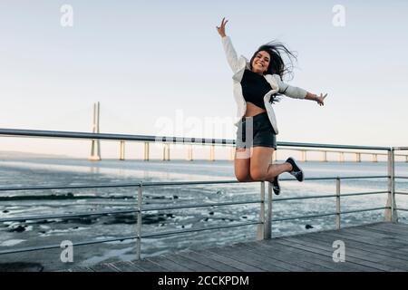 Junge Frau springt am Wasser Stockfoto