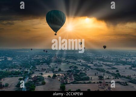 Myanmar, Mandalay Region, Bagan, Heißluftballons fliegen über alte Stupas bei dramatischem Sonnenaufgang Stockfoto