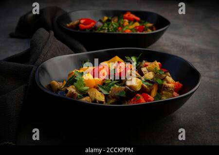 Zwei Schüsseln gebratener veganer Salat mit Auberginen, Paprika und Petersilie Stockfoto