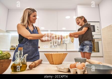 Fröhliche Mutter und Tochter kneten Pizzateig in der Küche bei Zu Hause Stockfoto