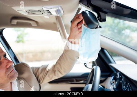 Porträt eines Mannes im Auto, der seine Schutzmaske abnimmt Stockfoto