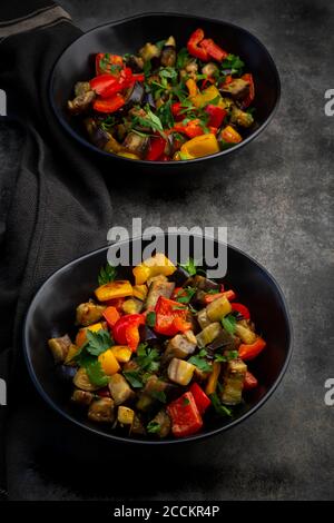 Zwei Schüsseln gebratener veganer Salat mit Auberginen, Paprika und Petersilie Stockfoto