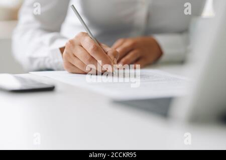 Nahaufnahme einer Geschäftsfrau, die am Schreibtisch zu Hause auf Papier schreibt Büro Stockfoto