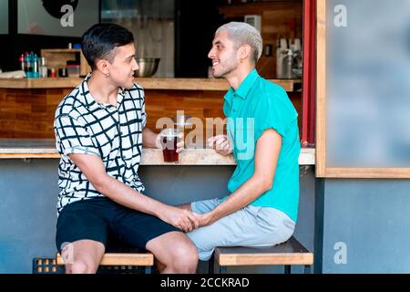 Loving Gay paar Hände halten, während sitzen an der Bar Zähler Stockfoto