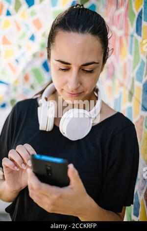 Porträt der Frau mit Smartphone vor der bunten Wand Stockfoto