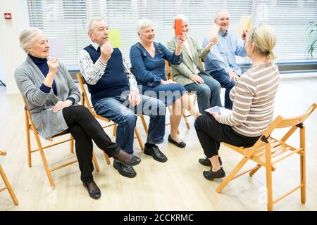 Senioren in Altersheim Teilnahme an Gruppentherapie mit bunten Papier Karten Stockfoto