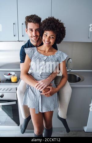 Romantische multi-ethnischen Paar umarmt in der Küche des Penthouse Stockfoto