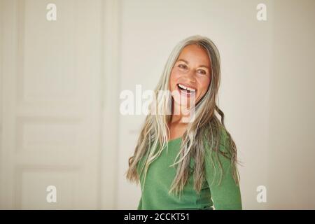 Lächelnde Frau zu Hause wegschauen Stockfoto