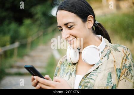 Frau lächelt, während SMS-Nachrichten von ihrem Smartphone Stockfoto