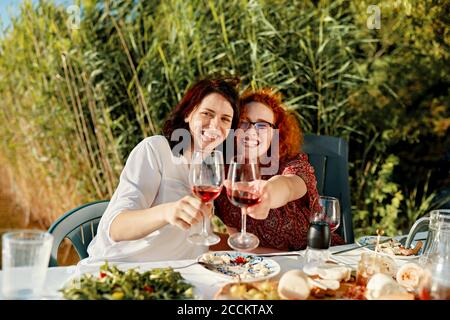 Portrait von zwei glücklichen Freundinnen beim Abendessen im Weingläser am See Stockfoto