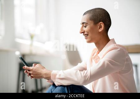 Glückliche Frau in einem Loft mit Smartphone Stockfoto