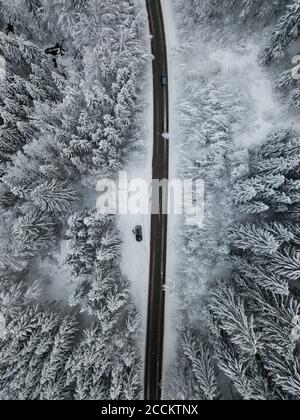 Luftaufnahme der Asphaltstraße Schnitt durch schneebedeckten Wald in Achtal Stockfoto