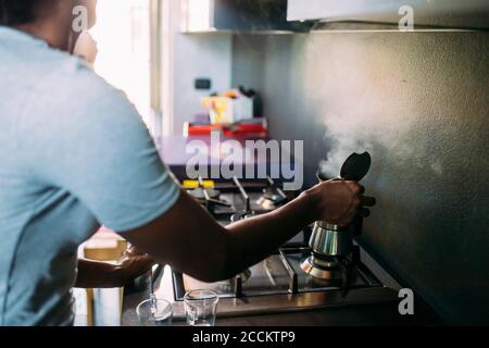 Nahaufnahme einer Frau, die Kaffee auf dem Herd in der Küche macht Stockfoto