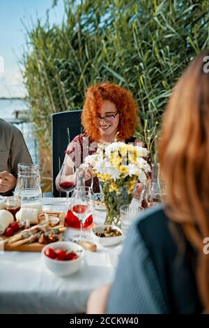Eine rothaarige Frau, die mit Freunden am See zu Abend gegessen hat Stockfoto
