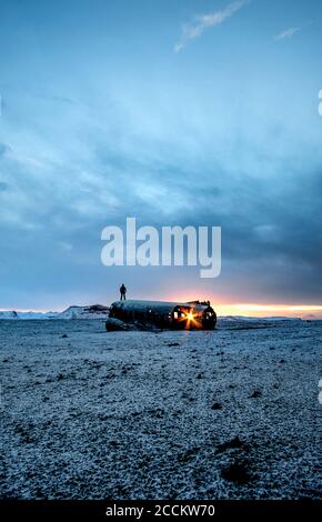 Silhouette eines Mannes, der auf einem alten Flugzeugwrack steht Bei Sonnenuntergang Stockfoto