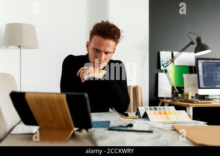 Durchdachte Architektin, die sich mit digitalen Tablets im Heimbüro umsieht Stockfoto