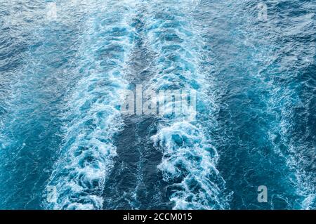 Stürmischer Schaum und eine Schiffsstrecke auf dem blauen Meerwasser. Stockfoto