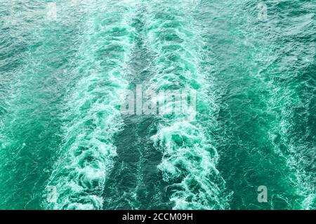 Stürmischer Schaum und eine Schiffsstrecke auf dem türkisfarbenen Meerwasser. Stockfoto