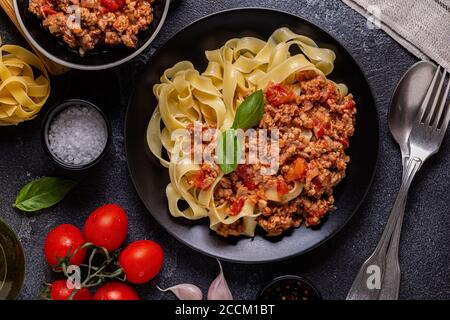 Traditionelle italienische Pasta Bolognese auf schwarzem Teller, Draufsicht. Stockfoto