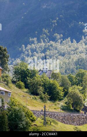 GEIRANGER, NORWEGEN - 2016. JUNI 14. Geiranger Kirche in großen grünen Bäumen. Stockfoto