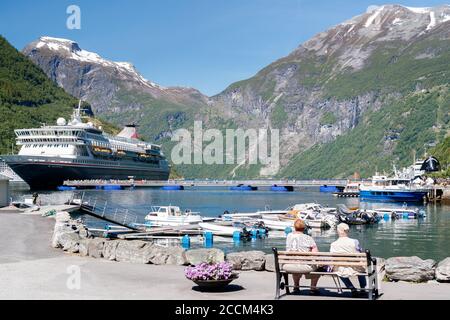 GEIRANGER, NORWEGEN - 2016. JUNI 14. Kreuzfahrtschiff im Fjord von Geiranger mit Schnee auf den Berggipfeln Stockfoto