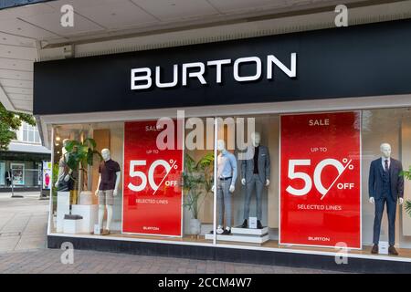 Ein Burton-Geschäft Schild über gekleideten Schaufensterpuppen und Verkaufsplakaten Im Fenster Stockfoto