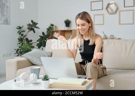 Blonde Frau in Casualwear erklärt ihrem Freund etwas Notebook-Display Stockfoto