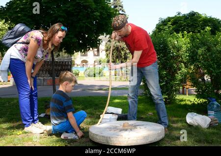 Mann und Junge sitzen in der Nähe Töpfer s Rad, männliche Töpfer lehrt Jungen Rad werfen, andere wathing. Juni 12,2019. Kiew, Ukraine Stockfoto