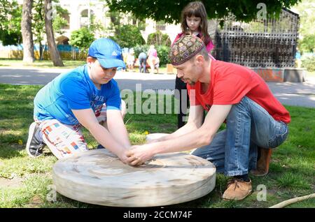 Männlicher Töpfer lehrt Junge von Rad werfen. Juni 12,2019. Kiew, Ukraine Stockfoto