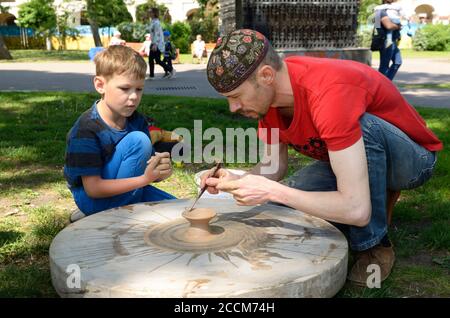 Männlicher Töpfer lehrt Junge von Rad werfen. Juni 12,2019. Kiew, Ukraine Stockfoto