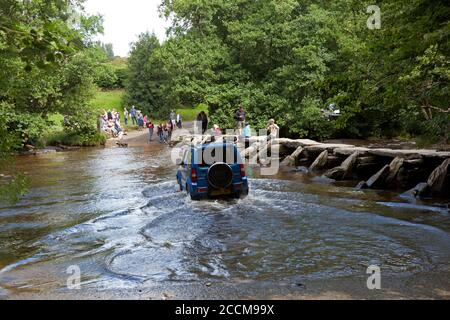 Ein Auto fährt durch den Fluss Barle an der Klappbrücke Tarr Steps im Exmoor Nationalpark, Somerset Stockfoto