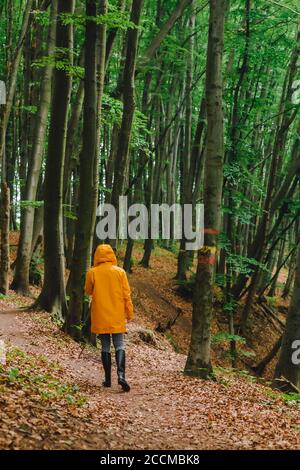Frau in gelber Regenjacke, die durch den Regenwald läuft Stockfoto