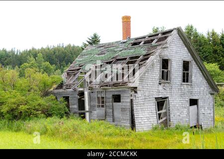 Ein altes verlassenes Haus in schlechtem Zustand. Ein Großteil des Dachs fehlt und es gibt kein Glas in den Fenstern. Es sieht so aus, als würde es bald umfallen. Stockfoto