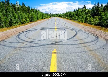 Mehrere Gleitspuren auf einer zweispurigen Autobahn. Viele kreisförmige Markierungen. Bäume säumen die Straße und der Himmel ist mostky blau oben. Heller, sonniger Tag. Stockfoto