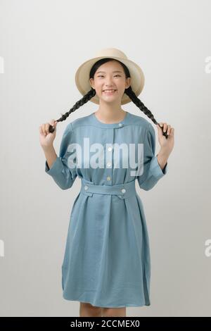 Gut aussehende asiatische Frau hält zwei Zöpfe in den Händen, schaut auf die Kamera mit zufrieden Ausdruck Stockfoto