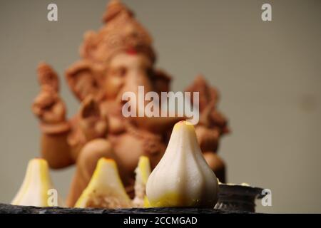 Modak- ein traditionelles Gericht auf Ganpati Festival in Indien. Serviert mit klarer Butter. Ganesh Idol im Hintergrund Stockfoto