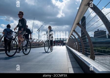 Die Menschen wandern und radeln über die Millennium Bridge, die berühmte wackelige Fußgängerbrücke über die Themse von St. Pauls zur Tate Modern in London Stockfoto