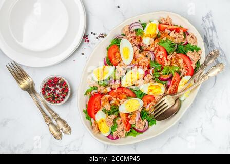 Thunfischsalat mit Salat, Tomaten, Eiern, roten Zwiebeln und einem zarten Dressing aus Olivenöl, Zitrone und Senf. Leichtes Gourmet-Abendessen. Selektiver Fokus Stockfoto