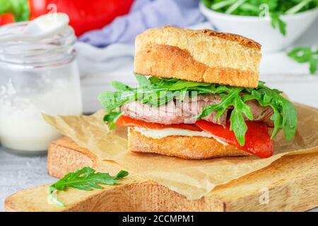 Delikatessensandwich mit Rindfleisch, gebackenen roten Paprika, Rucola und Meerrettichsauce. Gourmet-Snack. Selektiver Fokus Stockfoto