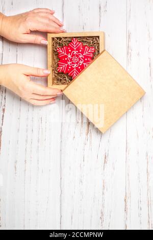 Lebkuchen in Puderzucker in Form von Schneeflocken. Traditionelles Neujahrs- und Weihnachtsgeschenk. Das Konzept der Feier. Frau packt Kekse i Stockfoto