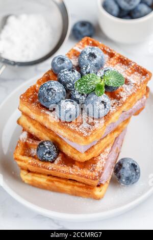 Traditionelle hausgemachte belgische (Wiener) Waffeln mit frischen Beeren, Heidelbeer-Souffle und Puderzucker. Leckeres Frühstück. Selektiver Fokus Stockfoto