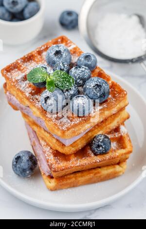 Traditionelle hausgemachte belgische (Wiener) Waffeln mit frischen Beeren, Heidelbeer-Souffle und Puderzucker. Leckeres Frühstück. Selektiver Fokus Stockfoto