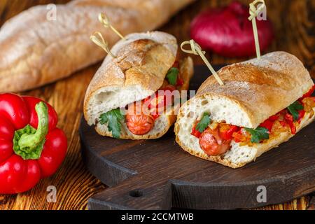 Hausgemachte leckere Sandwiches mit Wurst, rotem Paprika, karamellisierten Zwiebeln und Petersilie. Baguette. Selektiver Fokus Stockfoto