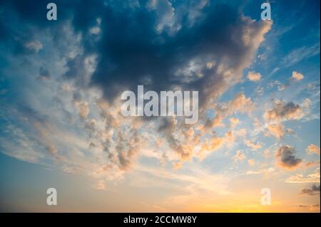 Schöner Sommerhimmel voller Wolken bei Sonnenuntergang zur goldenen Stunde. Interessante warme Farben am Horizont. Stockfoto