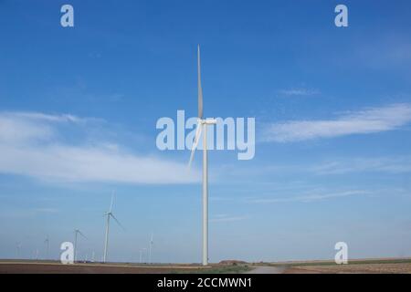 Windturbinen, die in einem Feld auf einem Hintergrund von installiert sind Blauer Himmel Stockfoto