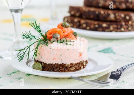 Mousse aus geräuchertem Lachs (Forelle), Quark (Ricotta) und Kräutern Dill mit Zitrone und Kapern auf Roggenbrot mit Samen. Canapes, Antipasti. Feinkost Stockfoto