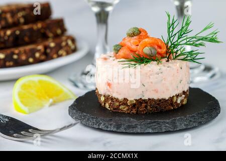 Mousse aus geräuchertem Lachs (Forelle), Quark (Ricotta) und Kräutern Dill mit Zitrone und Kapern auf Roggenbrot mit Samen. Canapes, Antipasti. Feinkost Stockfoto