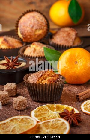 Frisch gebackene hausgemachte Zitrusfrüchte (Orange, Mandarine) Kuchen Muffins mit braunem Zucker, Zimt und Sternanis in schwarzem Teflon Backform über auf Holztabl Stockfoto